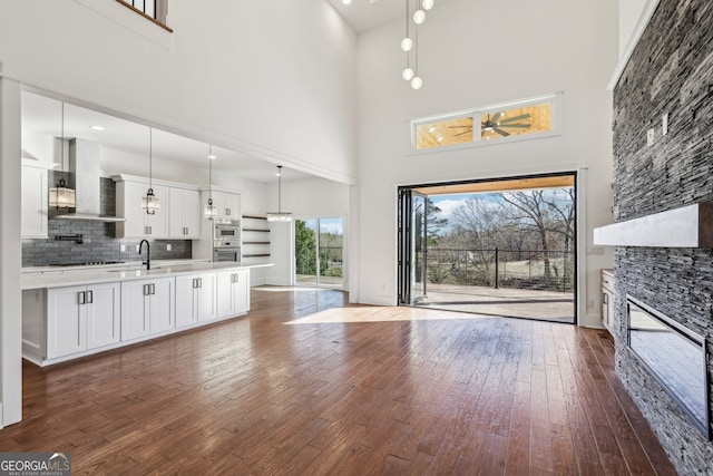 living room with a fireplace, sink, a high ceiling, and dark hardwood / wood-style floors