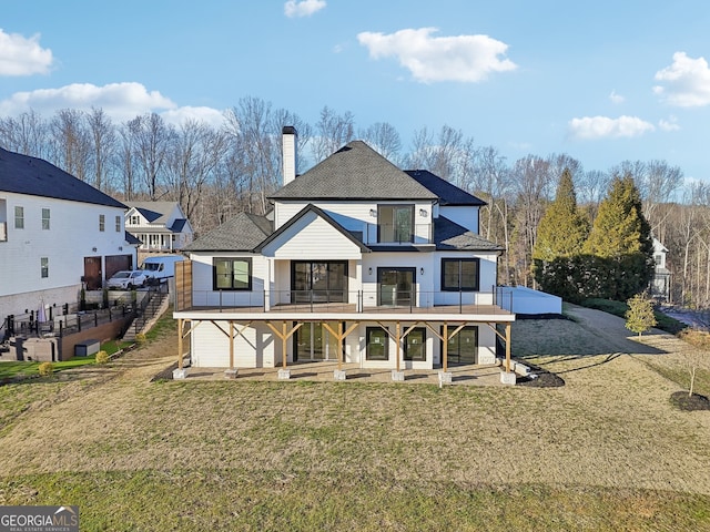 rear view of house featuring a yard and a balcony