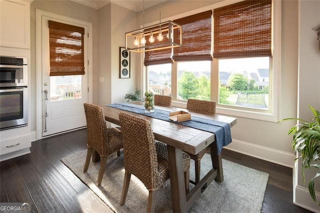 dining space with baseboards, dark wood-type flooring, a notable chandelier, and crown molding