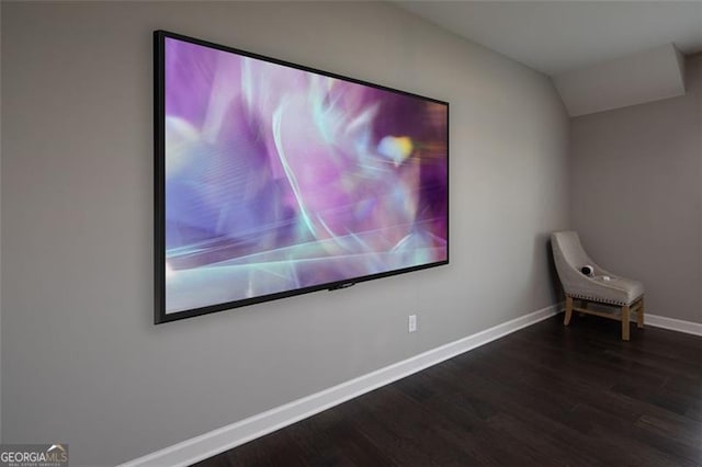 home theater room with lofted ceiling, dark wood finished floors, and baseboards