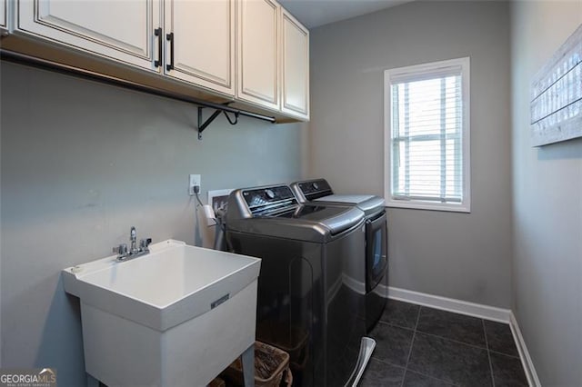 laundry area with washing machine and dryer, dark tile patterned floors, a sink, baseboards, and cabinet space