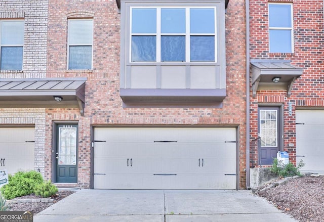 view of front facade with brick siding, concrete driveway, a standing seam roof, metal roof, and a garage