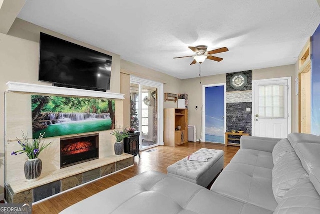 living room with hardwood / wood-style flooring, ceiling fan, and a high end fireplace