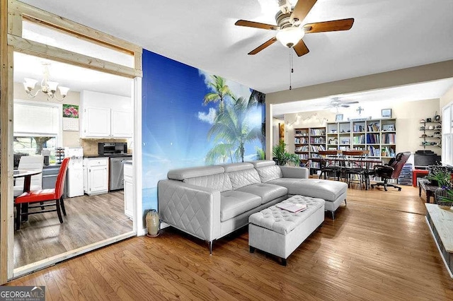 living room featuring ceiling fan with notable chandelier and hardwood / wood-style flooring