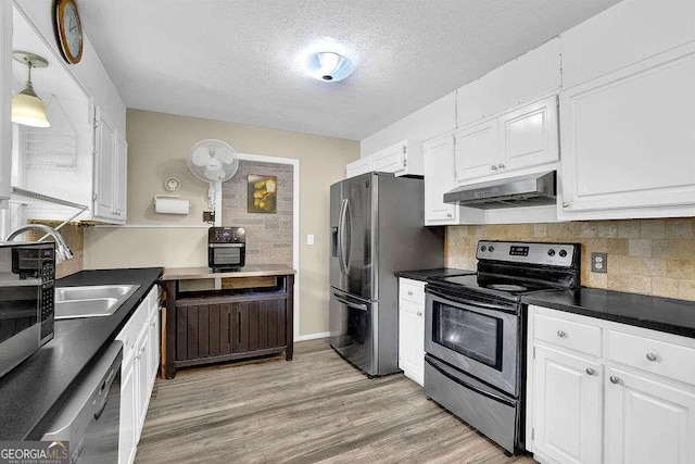 kitchen featuring light hardwood / wood-style floors, exhaust hood, appliances with stainless steel finishes, white cabinets, and decorative backsplash