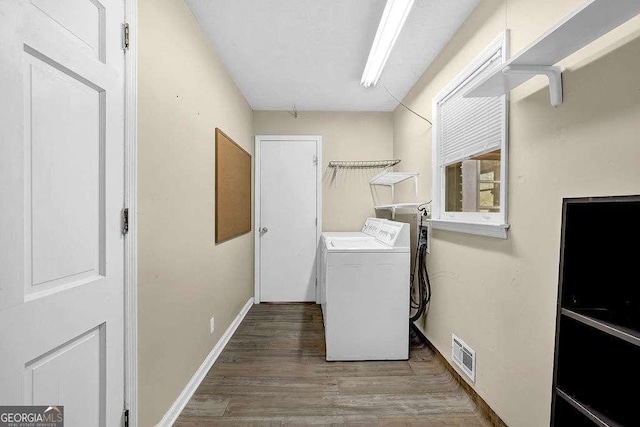 clothes washing area featuring washer and clothes dryer and wood-type flooring