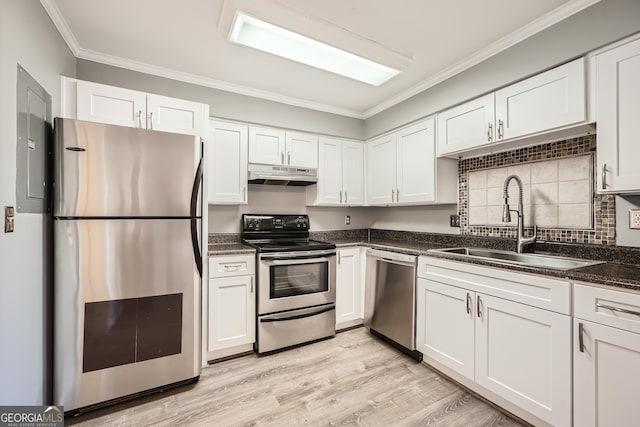 kitchen with ornamental molding, stainless steel appliances, under cabinet range hood, white cabinetry, and a sink