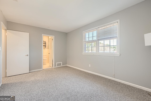 unfurnished bedroom with carpet, connected bathroom, visible vents, and baseboards