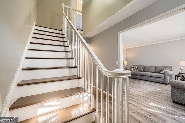 staircase featuring crown molding and wood finished floors