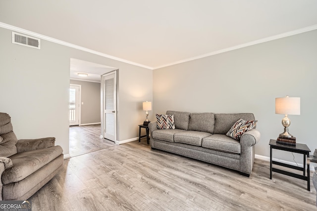 living area with light wood-style flooring, visible vents, baseboards, and ornamental molding