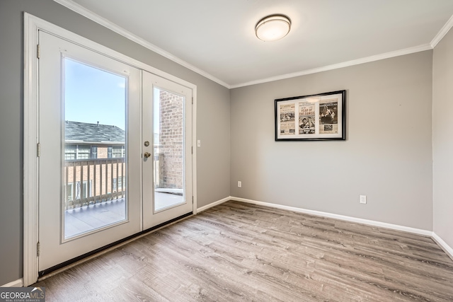 entryway with light wood-type flooring, baseboards, ornamental molding, and french doors