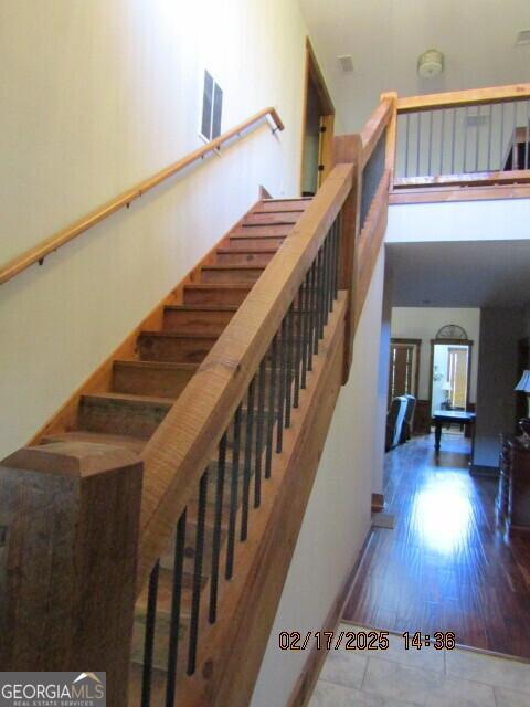 stairway with a towering ceiling and wood-type flooring