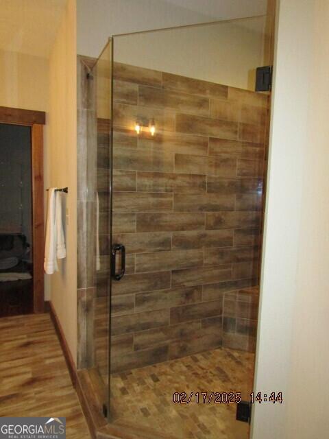 bathroom with hardwood / wood-style flooring and a shower with door