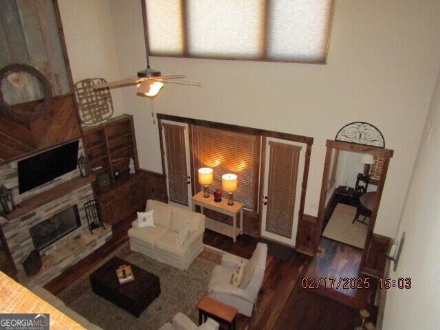 living room featuring a fireplace, dark wood-type flooring, and ceiling fan