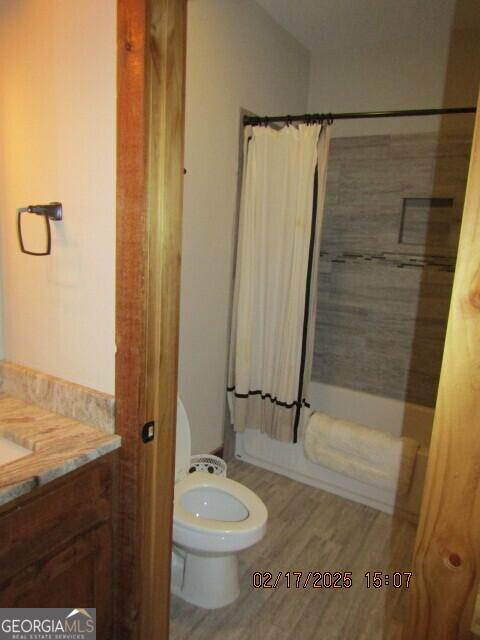 full bathroom featuring hardwood / wood-style flooring, vanity, toilet, and shower / tub combo with curtain