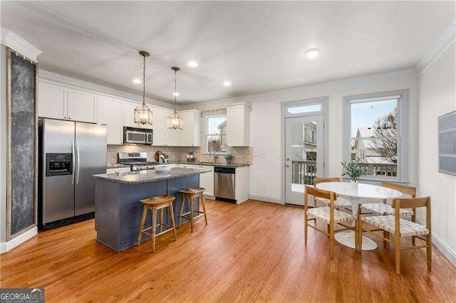 kitchen with a kitchen island, stainless steel appliances, pendant lighting, and white cabinets