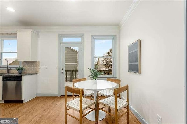 dining room featuring sink, light hardwood / wood-style floors, and crown molding