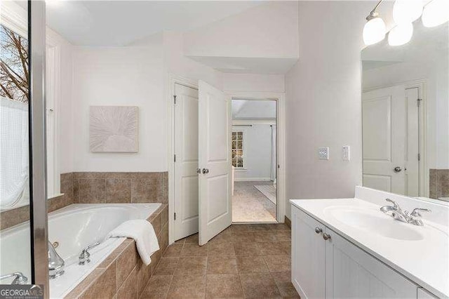 bathroom featuring vanity, tile patterned floors, and tiled bath