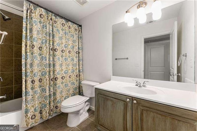 bathroom with toilet, vanity, and tile patterned flooring