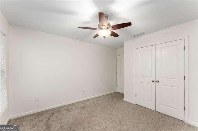 unfurnished bedroom with ceiling fan, light carpet, and a closet