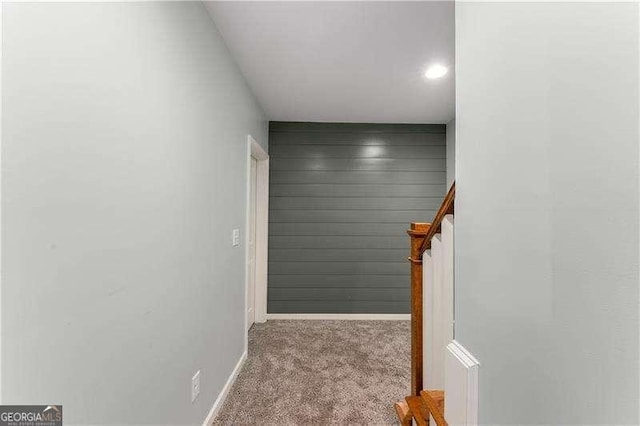 hallway featuring wood walls and light colored carpet