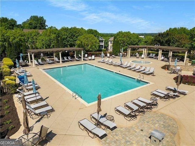 view of pool with a community hot tub, a pergola, and a patio area