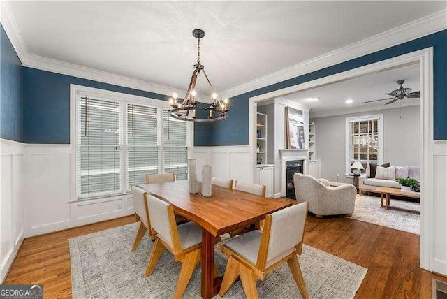 dining room featuring hardwood / wood-style flooring, crown molding, and ceiling fan with notable chandelier