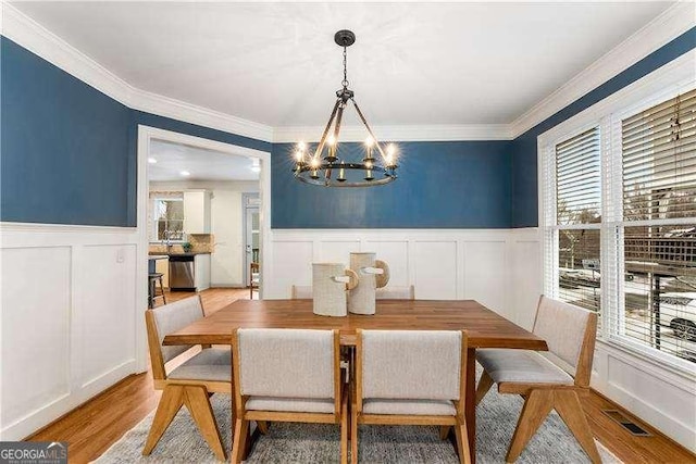 dining room featuring light wood-type flooring, crown molding, and an inviting chandelier