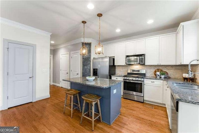 kitchen with white cabinets, stainless steel appliances, a kitchen island, and sink