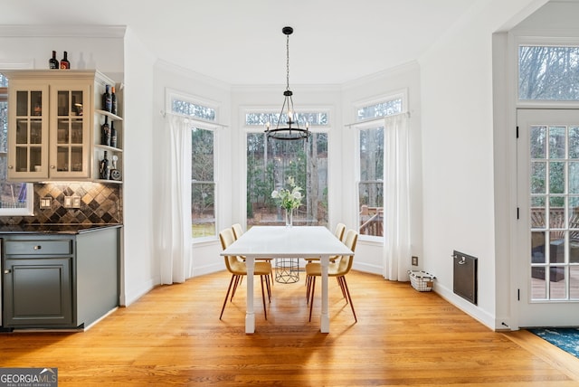 dining space with light wood-type flooring, a chandelier, and crown molding