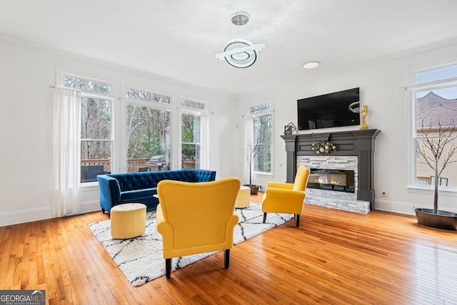 sitting room featuring a fireplace, ornamental molding, and wood-type flooring