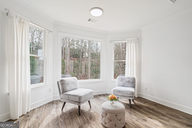 sitting room with a healthy amount of sunlight, wood-type flooring, and crown molding