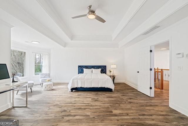 bedroom with a tray ceiling, ornamental molding, dark hardwood / wood-style floors, and ceiling fan