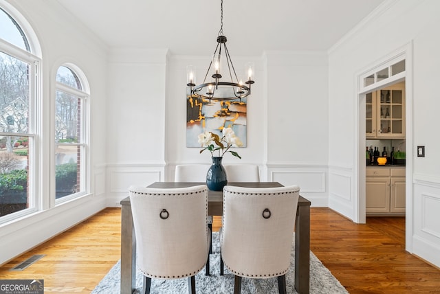 dining space featuring ornamental molding, an inviting chandelier, and light hardwood / wood-style floors