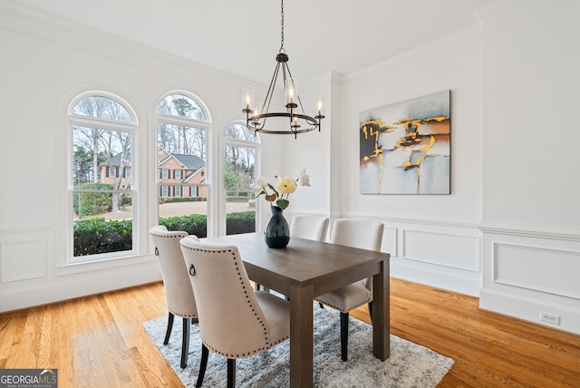 dining area with a notable chandelier, ornamental molding, and light wood-type flooring