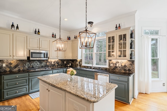 kitchen with hanging light fixtures, stainless steel appliances, dark stone counters, a center island, and sink