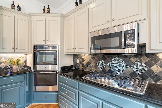 kitchen with appliances with stainless steel finishes, ornamental molding, blue cabinets, and tasteful backsplash