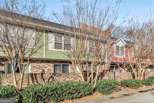 view of front facade with brick siding and fence