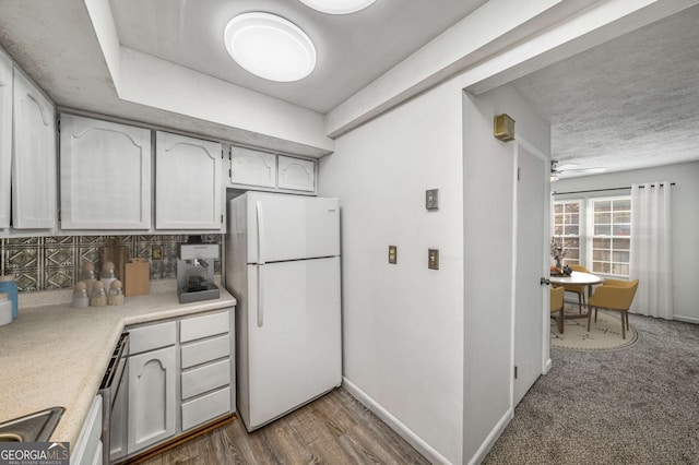 kitchen featuring freestanding refrigerator, light countertops, decorative backsplash, and ceiling fan