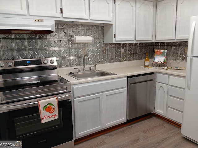 307 Adair St Unit E7, Decatur, GA 30030 - kitchen featuring appliances with stainless steel finishes, range hood, a sink, white cabinetry, and light countertops