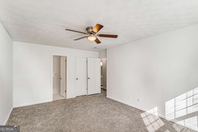 unfurnished bedroom featuring baseboards, a textured ceiling, carpet, ceiling fan, and ensuite bathroom