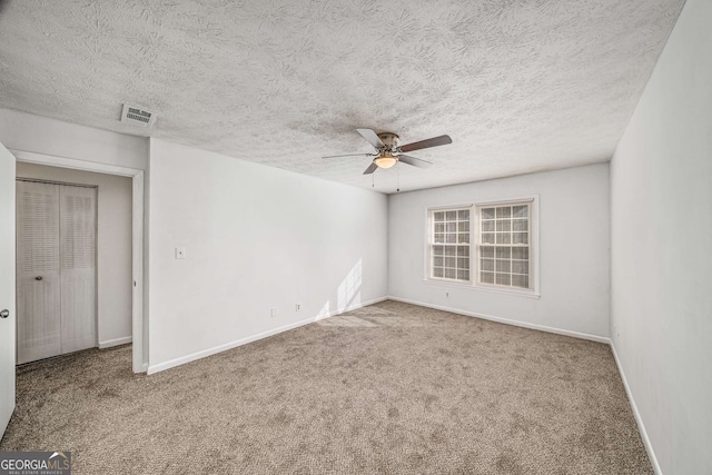 empty room with a ceiling fan, carpet flooring, baseboards, and a textured ceiling