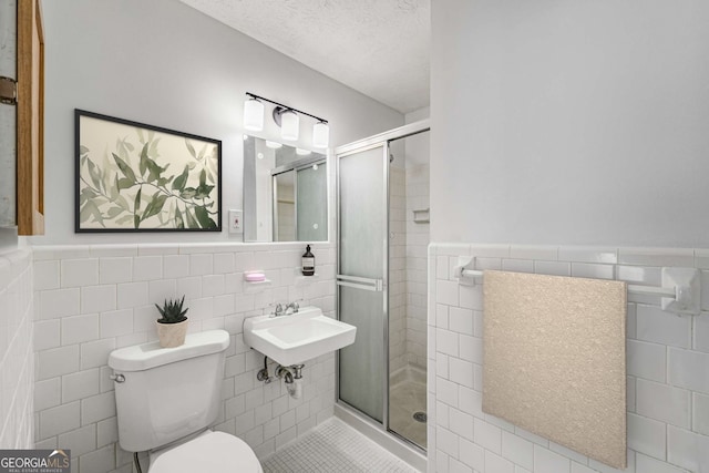 full bathroom featuring tile walls, a stall shower, wainscoting, toilet, and tile patterned floors
