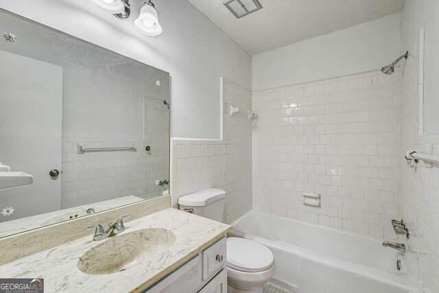 bathroom with toilet, washtub / shower combination, tile walls, vanity, and a wainscoted wall