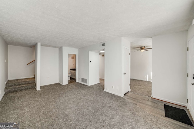 basement featuring a ceiling fan, baseboards, stairway, a textured ceiling, and carpet