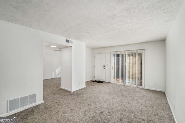 unfurnished room with carpet and a textured ceiling