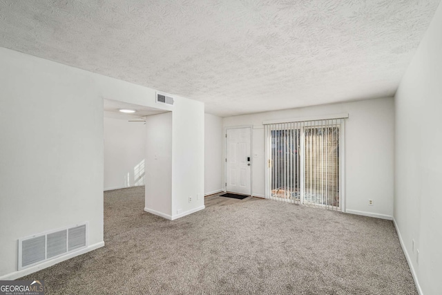 carpeted empty room featuring baseboards and a textured ceiling