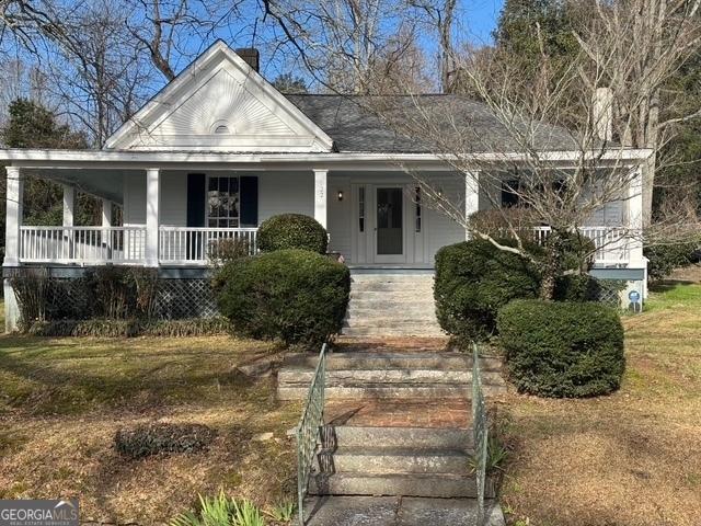 farmhouse-style home with a front lawn and a porch