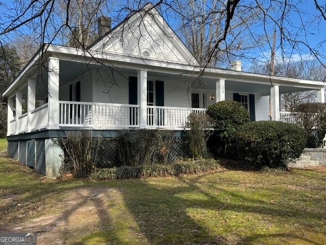 view of side of property featuring covered porch and a lawn