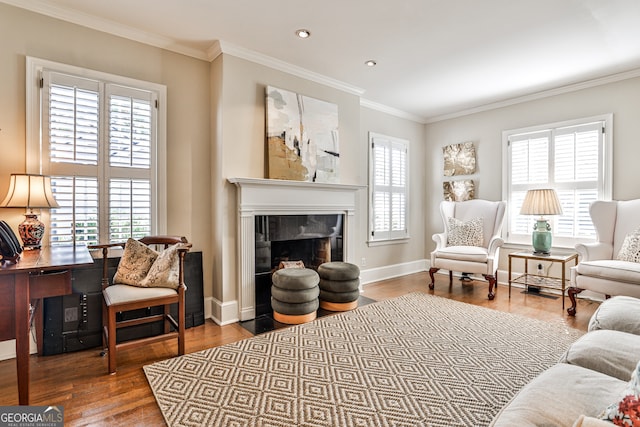 living area featuring hardwood / wood-style flooring, crown molding, and a tiled fireplace